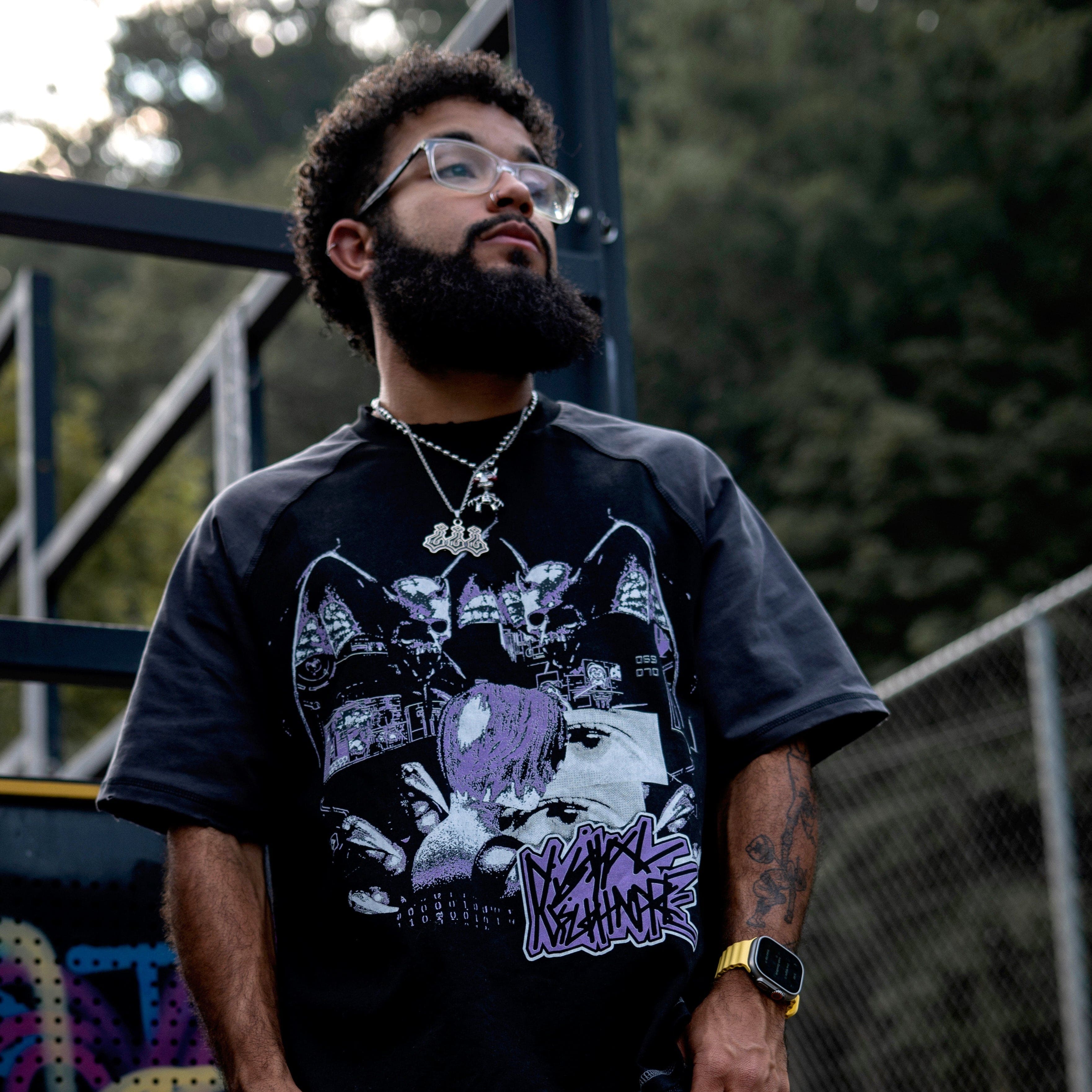 Man wearing a graphic t-shirt and ripped jeans standing outdoors.